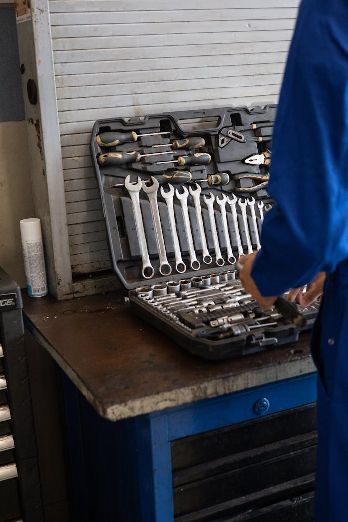 Mechanic in blue overalls organizing a toolset in an industrial workshop.
